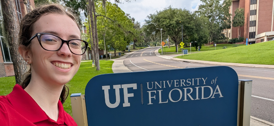 Claire Slusser takes a selfie by an outdoor sign at the University of Florida.