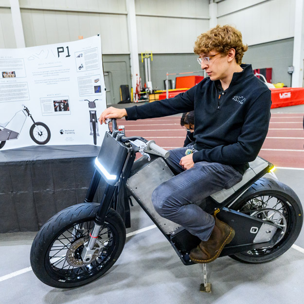 A student rides the electric motorcycle at the Rose Show. 