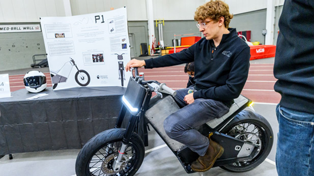 A student rides the electric motorcycle at the Rose Show. 
