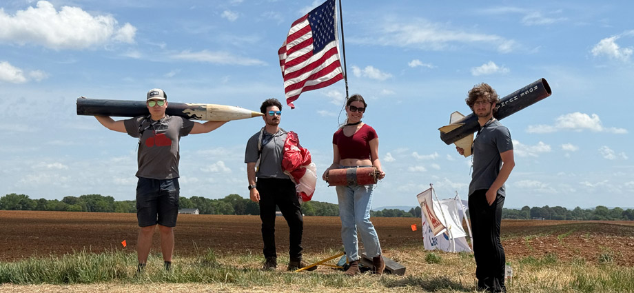 Four students hold rockets and an American flag.
