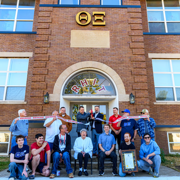 Theta Xi alumni and students and Erik Hayes cut a ribbon in fron of the new house.