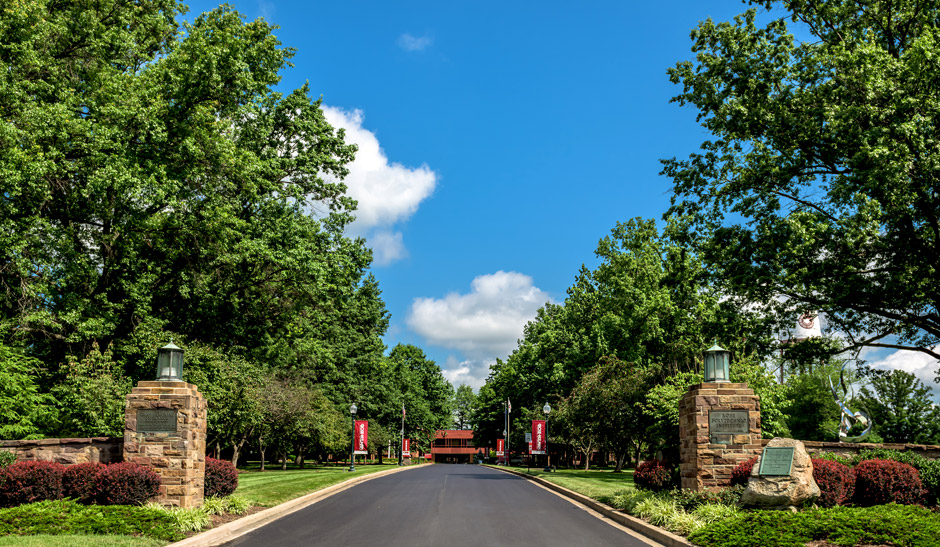 The entrance to Rose-Hulman with Hadley Hall in the distance and stone pillars in the foreground.
