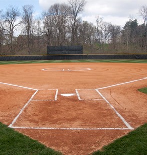 Image shows the Softball Field from behind home plate. The chalk lines are drawn in the orange dirt showing the field is ready for a softball game.